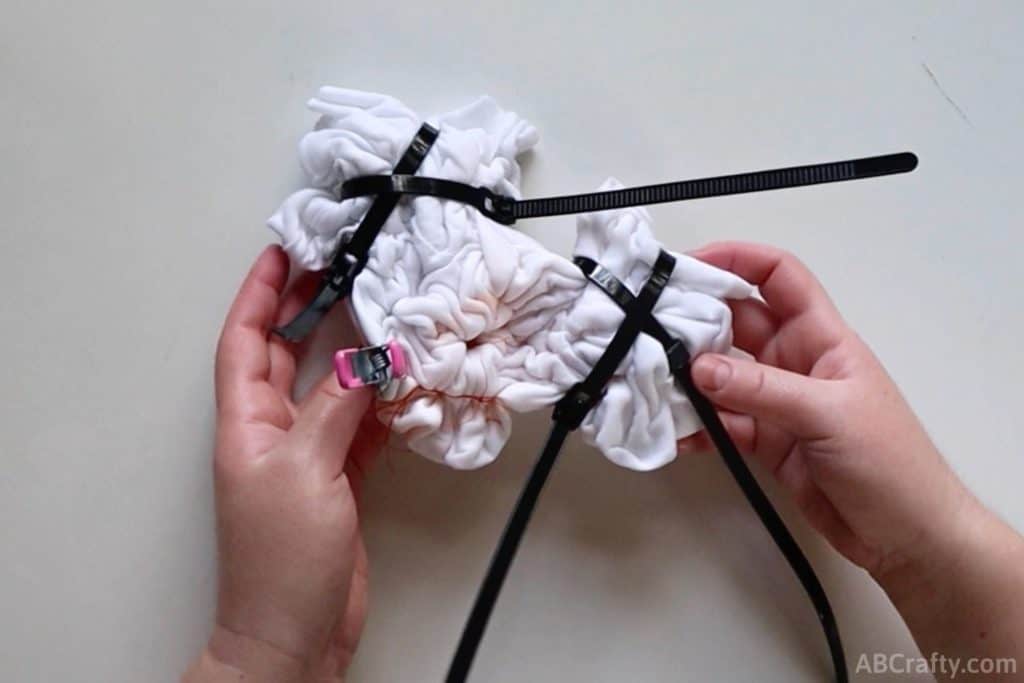 holding a tied up white shirt with zip ties