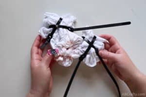 holding a tied up white shirt with zip ties