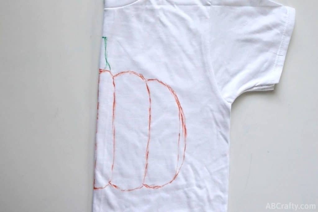 half of a pumpkin drawn on a folded white shirt as the template for a tie dye pumpkin