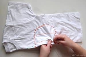 sewing the lines of the middle of a pumpkin on a folded shirt for a tie dye pumpkin design