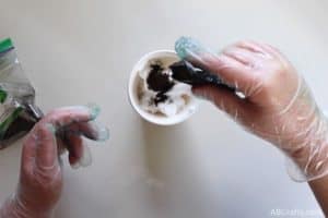shaking green idye poly into a cup with shaving cream