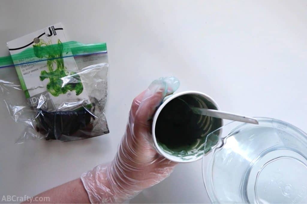 pouring water into a cup with shaving cream and green idye poly dye