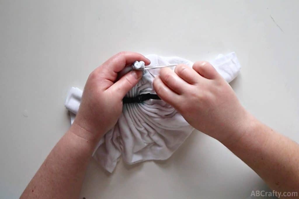 tying a rubber band around a small part of the white shirt