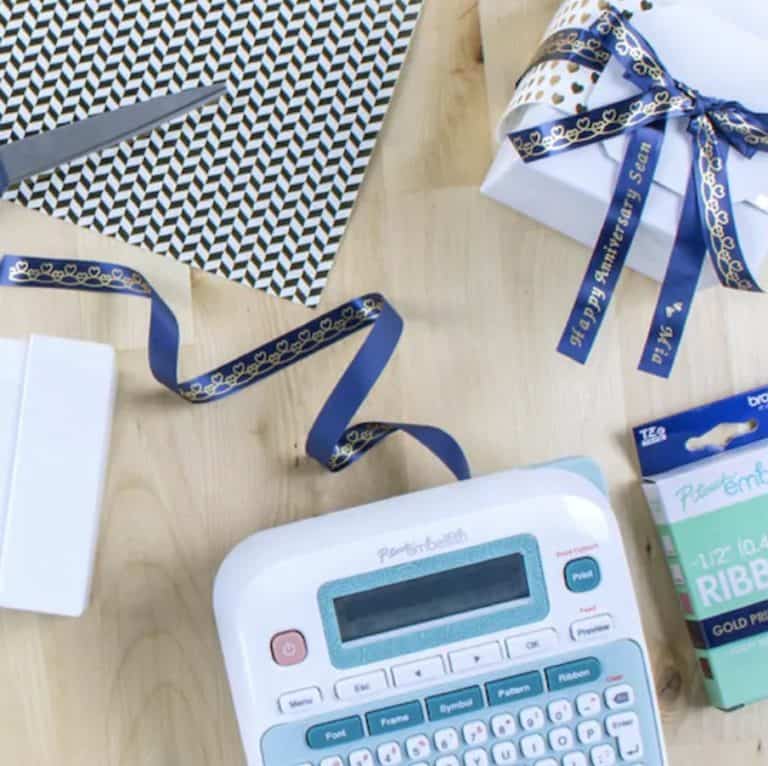 Brother p-touch embellishment ribbon and tape printer with the ribbon printing out of the machine and wrapped around a present