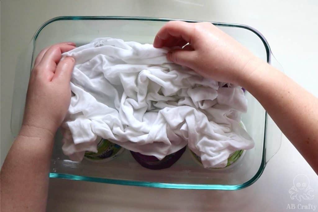 Scrunching a white cotton shirt elevated in a glass 9x13 pan