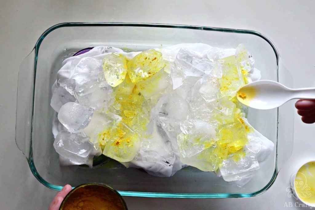 Sprinkling bright yellow dye powder on top of ice in two rows on top of a white shirt