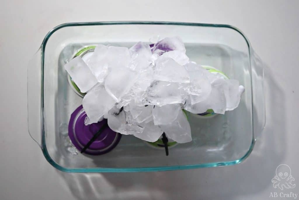 Ice cubes covering a shirt on top of yogurt containers in a glass 9x13 pan