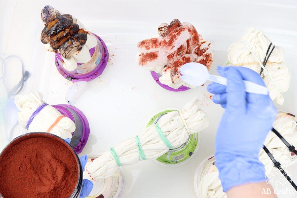 using a plastic spoon to sprinkle dye over ice onto tied tote bags using a jacquard ice dye