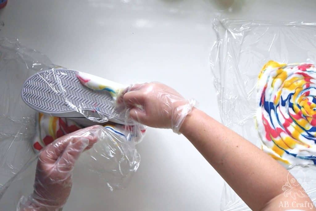 wrapping a white sneaker with plastic wrap that is filled with shaving cream and swirled with dye