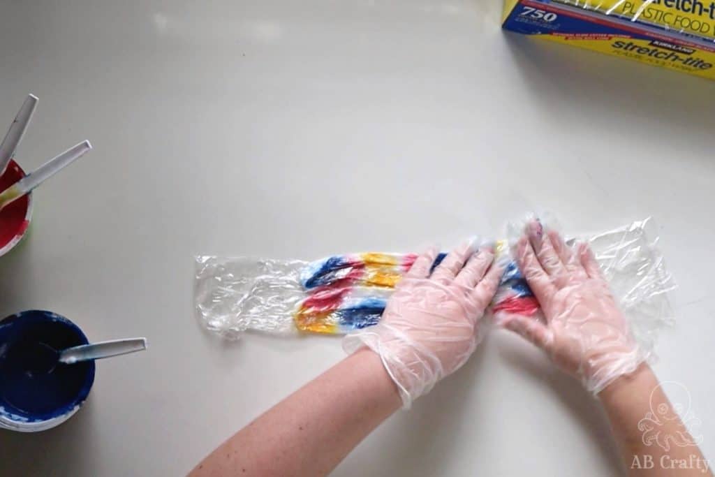 pressing tie dye onto white shoelaces wrapped with plastic wrap