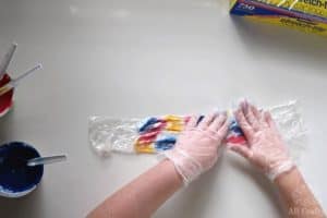 pressing tie dye onto white shoelaces wrapped with plastic wrap