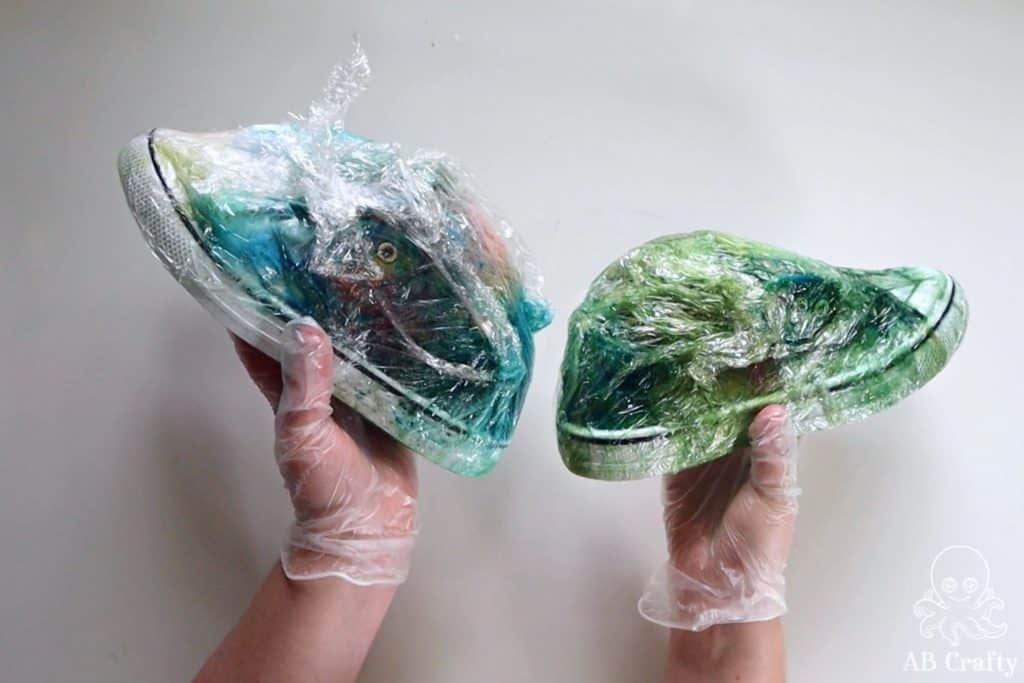 holding two converse covered in tie dye and wrapped in plastic