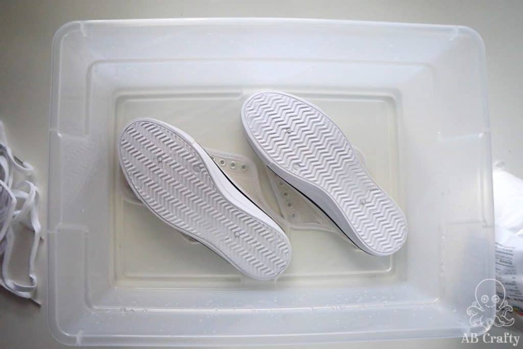 sneakers without laces soaking in a bath of soda ash