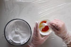 mixing shaving cream into a yogurt container containing yellow dye