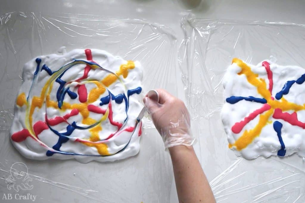 using the back of a plastic spoon to swirl tie dye throughout shaving cream