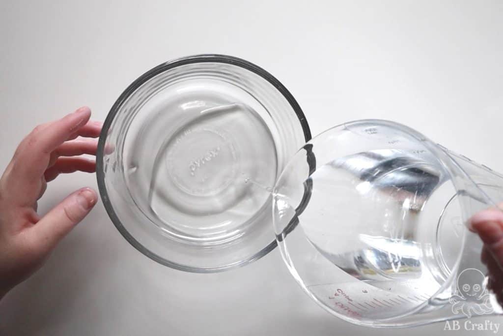 pouring water into a glass bowl containing clear glue