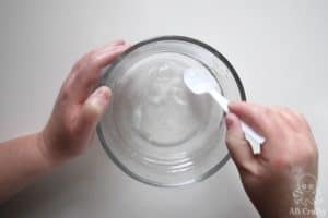mixing clear glue and activator with a plastic spoon to start to form clumps