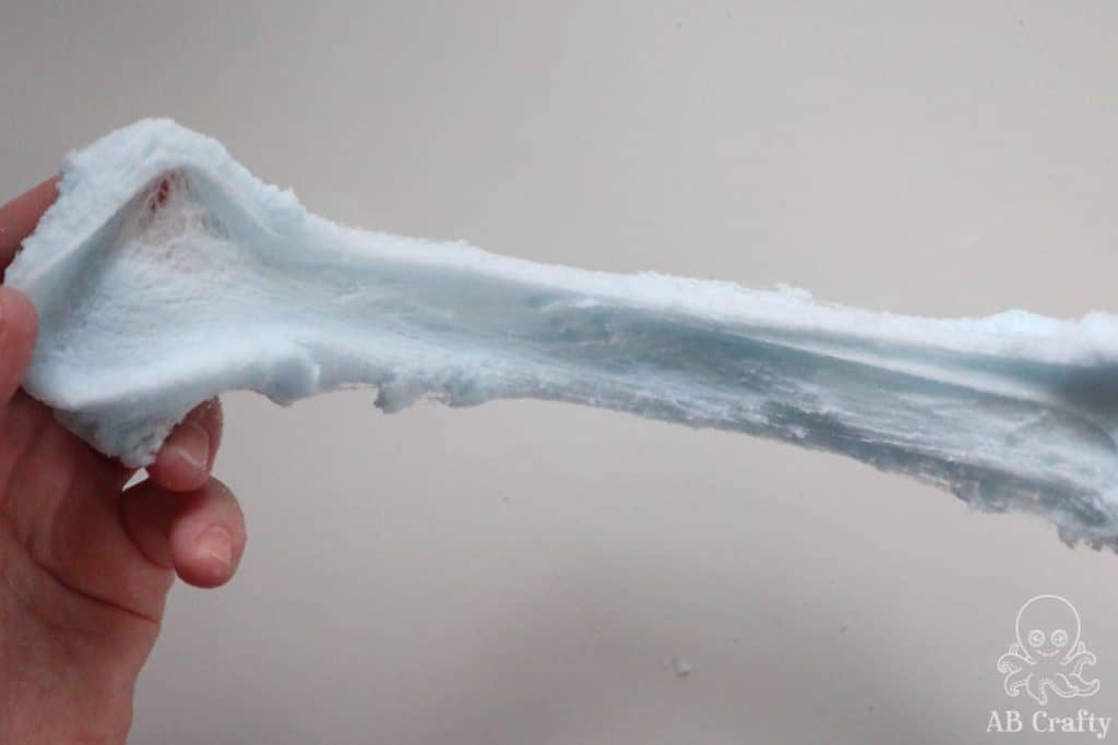 stretching blue snow slime so that it starts form strings