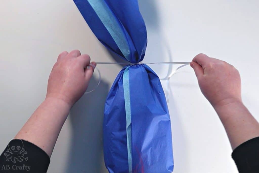 tying silver ribbon around the top of the present