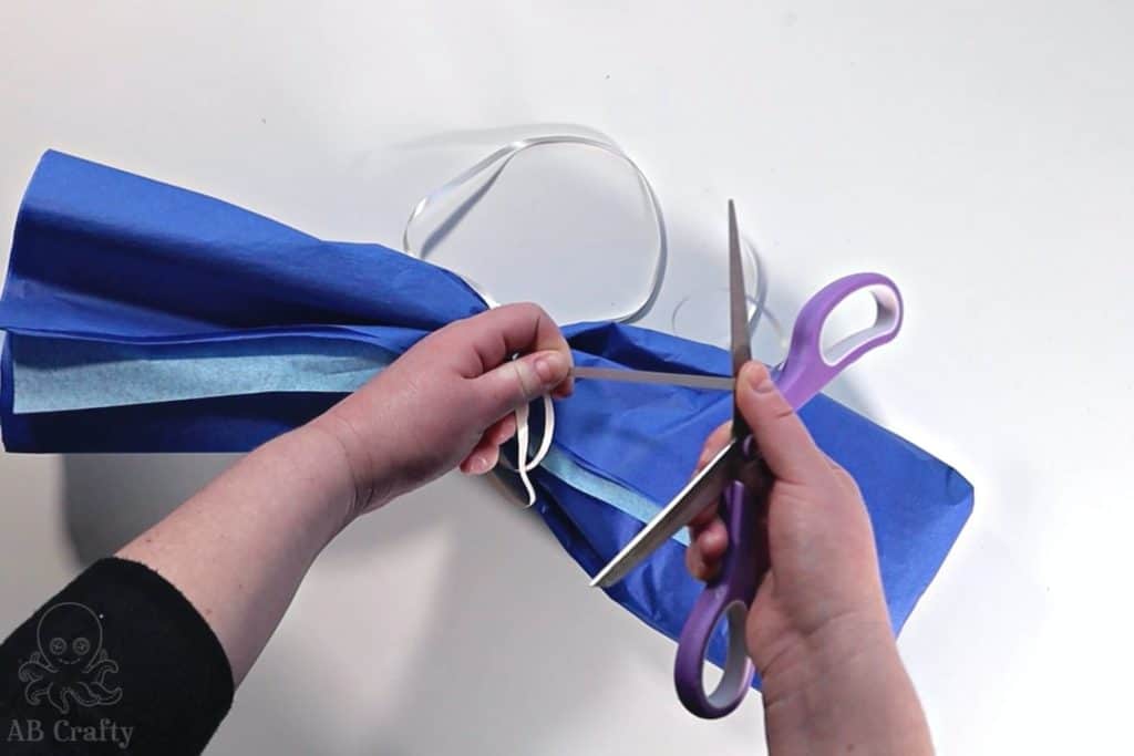 pulling the scissors up the ribbon with the thumb on top