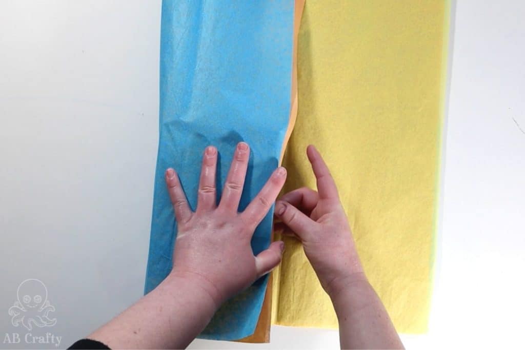 taping orange, yellow, and blue tissue paper to a box