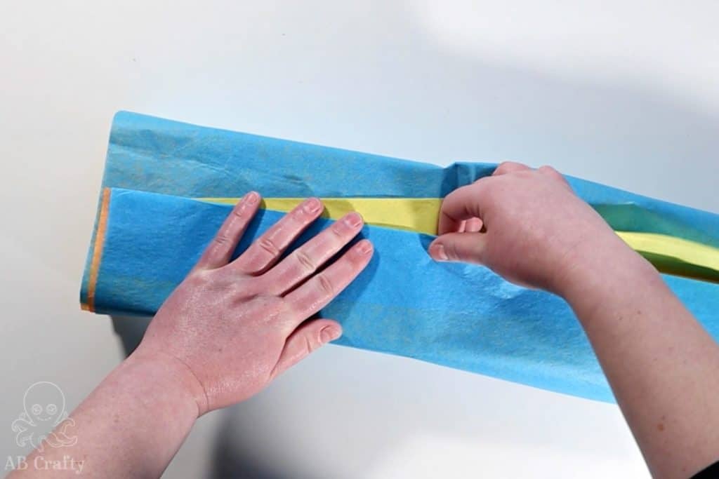 folding the blue tissue paper to meet the orange paper