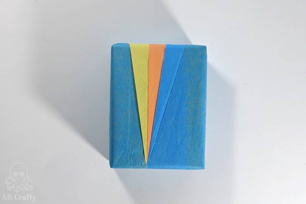 finished gift wrapped box with blue orange and yellow tissue paper forming triangles in an origami style gift wrap