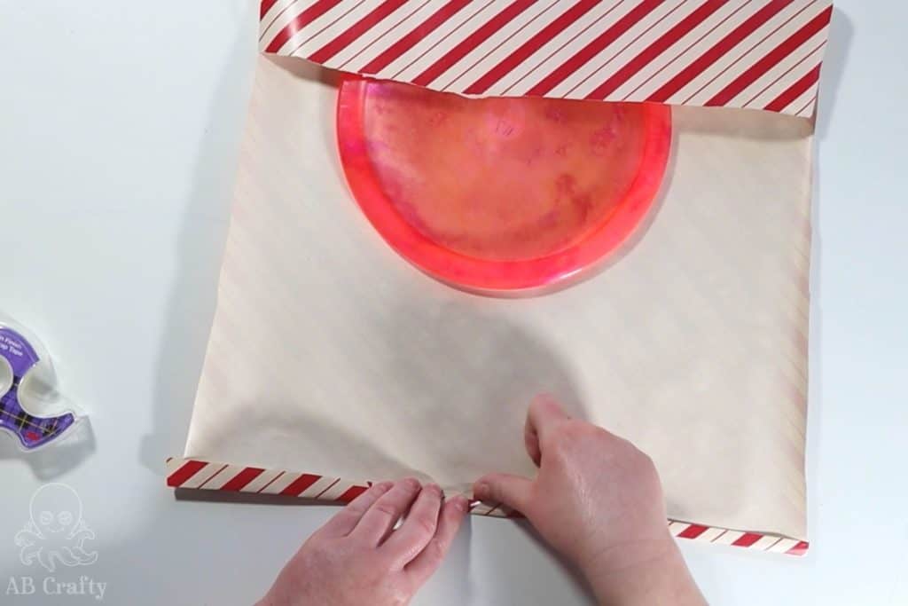adding tape to the edge of the wrapping paper to wrap a dyed frisbee golf disc