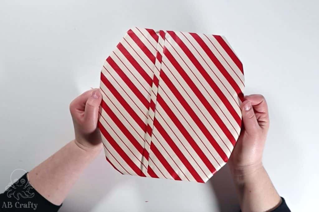 finished gift wrapped frisbee golf disc with red and white striped wrapping paper and a stripe of origami fold