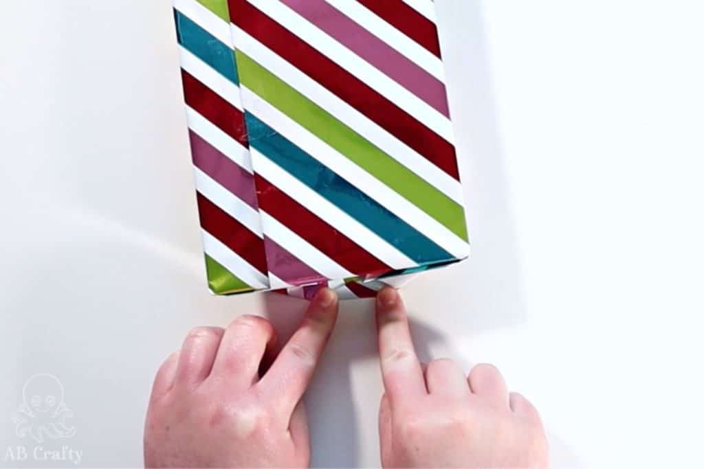 folding the edge of the corner of the paper on the side of the gift