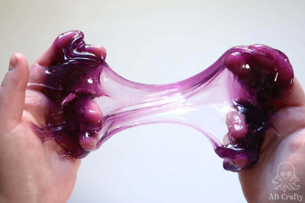 stretching purple clear slime so that it's see through in the middle