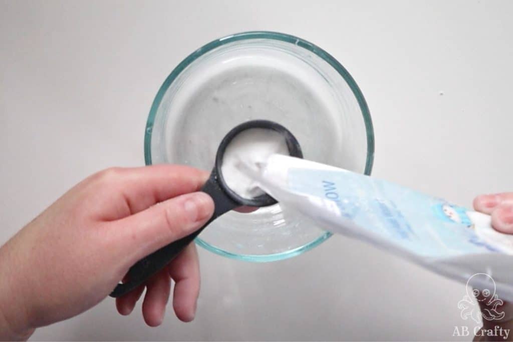 pouring instant snow into a measuring spoon