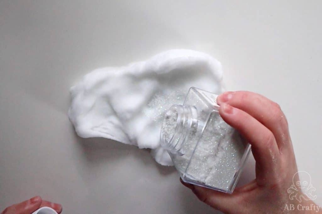 shaking white glitter onto slime