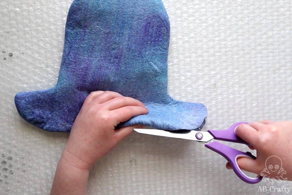 using scissors to cut the bottom of the hat