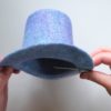 opening the alligator clip while holding the blue wet felted mini top hat