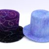 two wet felted top hats. one is black and purple with rainbow swirls and the other is in blue tones