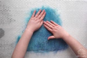 pressing the water into the wool with hands
