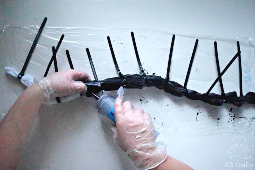 squeezing black dye from a squirt bottle onto tied shirt