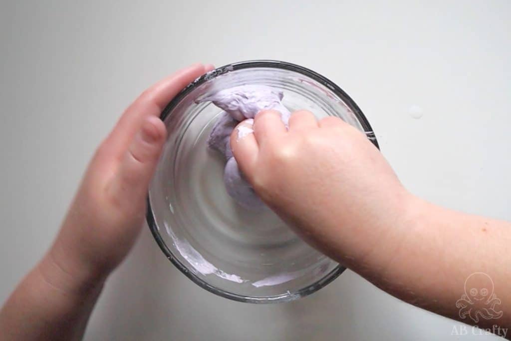 rolling the purple slime around in the bowl to get the slime stuck to the edges of the bowl