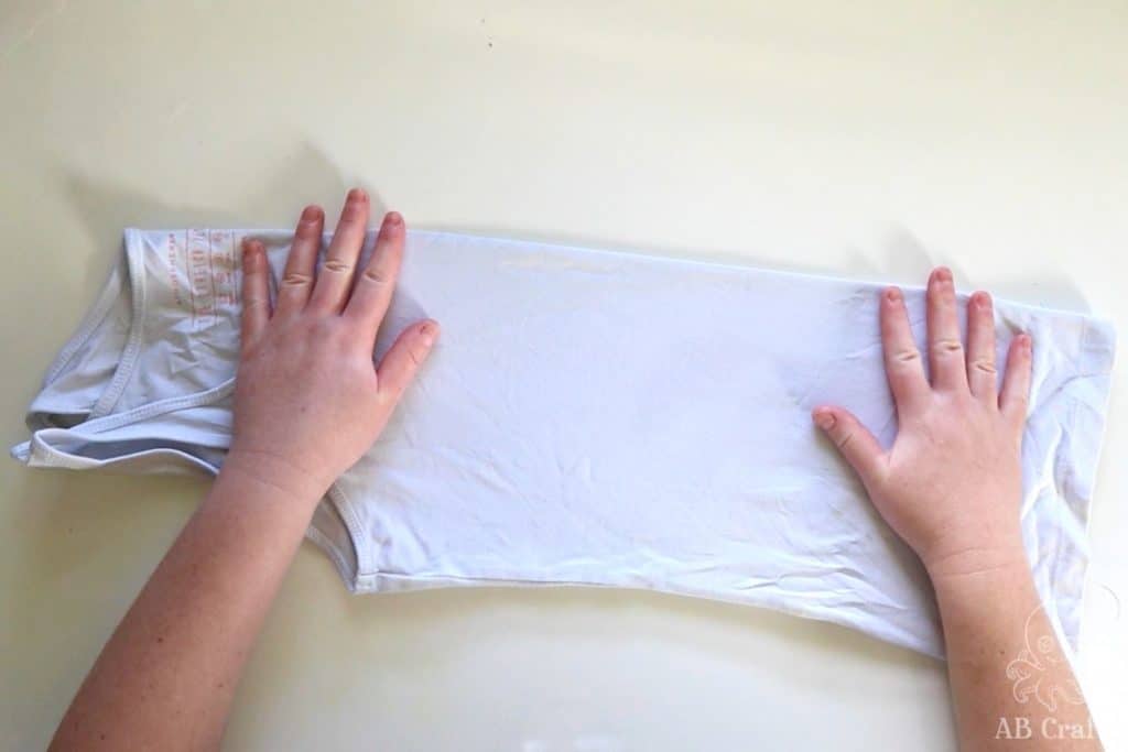 folding a white cotton tank top in half