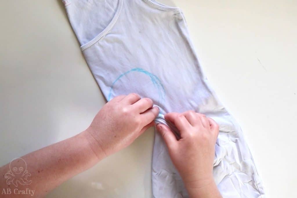 pinching folds along the outline of a heart on a white tank top