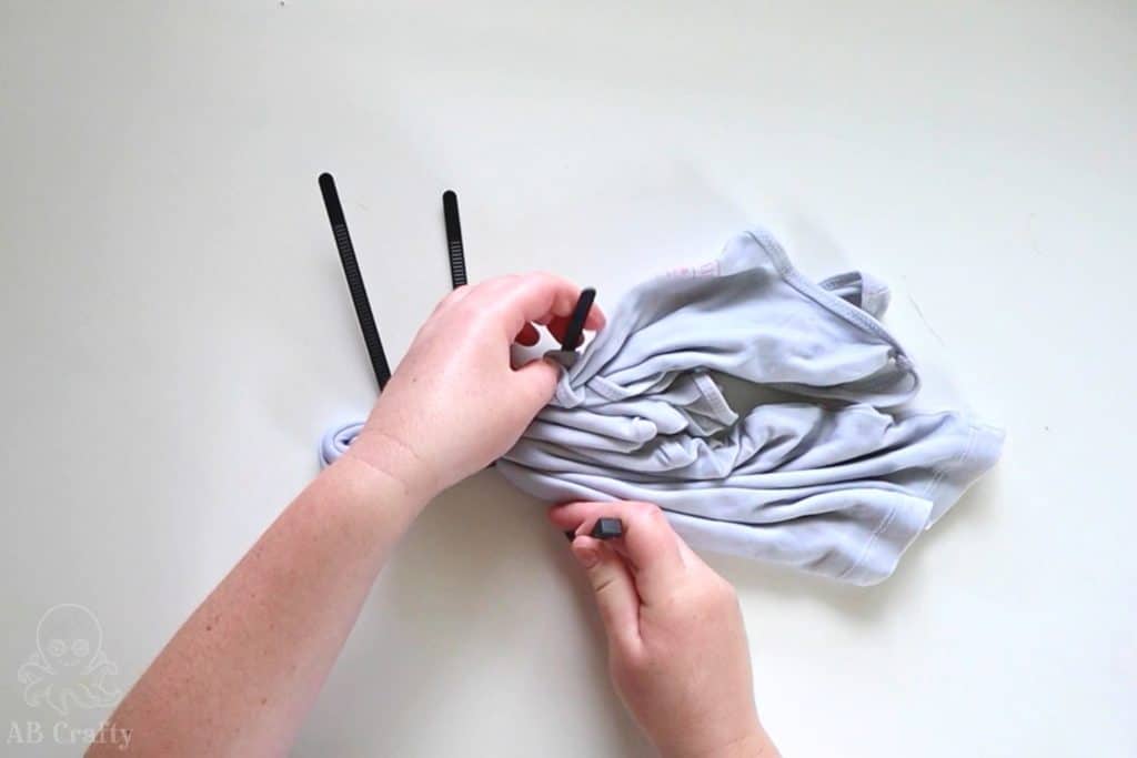 adding zip ties onto a folded white shirt
