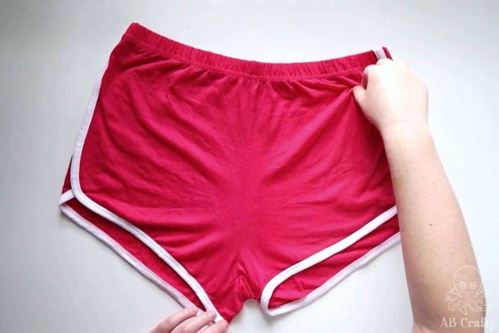 pinching the top corner of bright pink american apparel shorts with white trim
