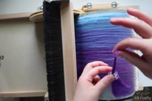 pulling purple wool through a sewing machine bobbin