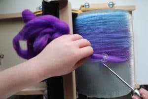 using an awl to pick up fibers on the barrel of a carder