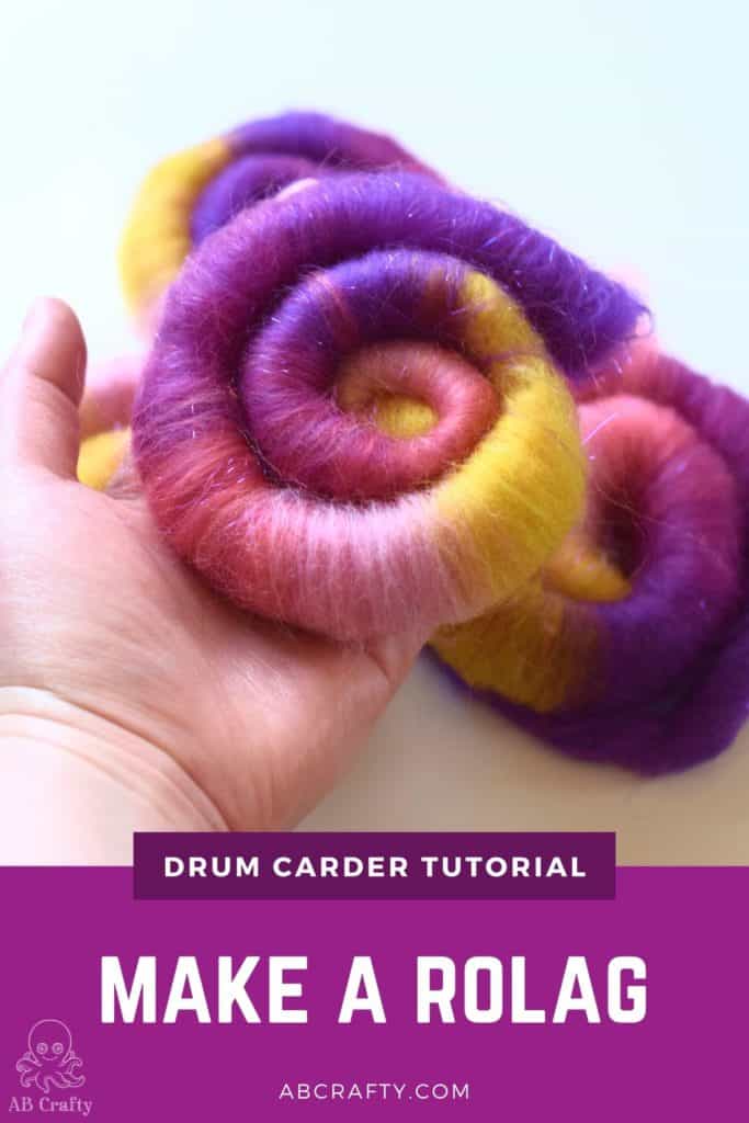holding a finished pink, purple, and yellow wool rolag with the title "drum carder tutorial - make a rolag, abcrafty.com"