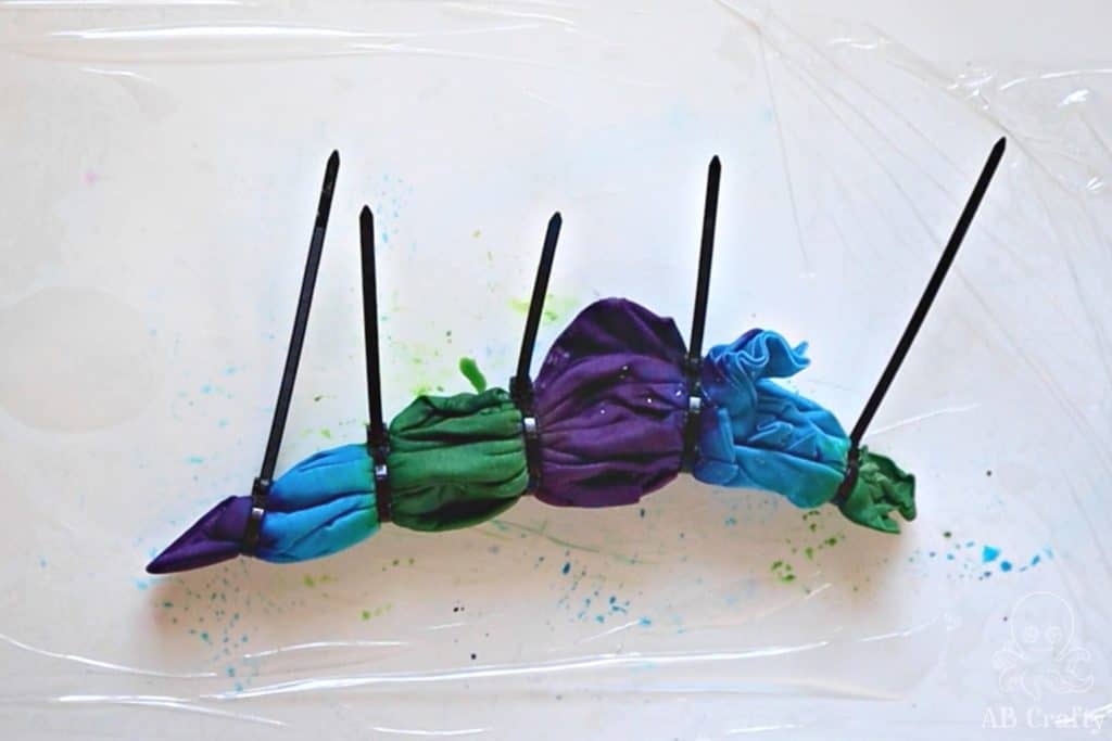 completely dyed shirt wrapped in zip ties with sections of blue, green, and purple