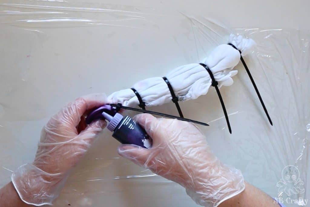 adding purple dye to a section of shirt wrapped in zip ties