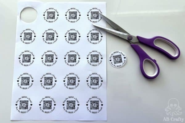 cutting out one of the qr codes from the printable buy the bride a drink venmo bracelet template