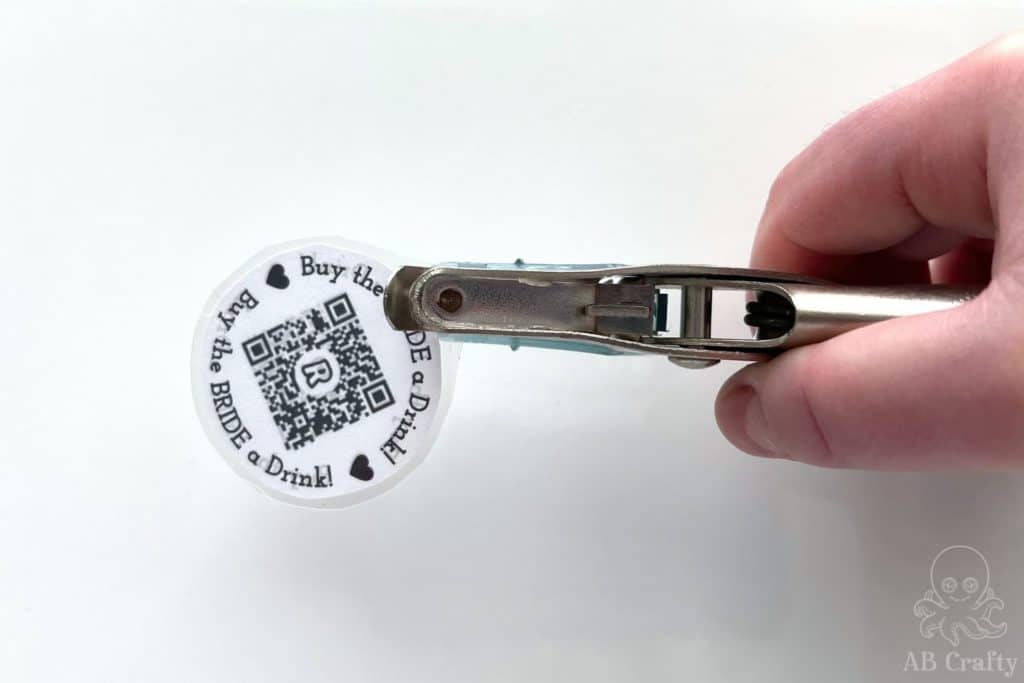 using a hole punch to punch a hole at the top of the printed and laminated venmo QR code